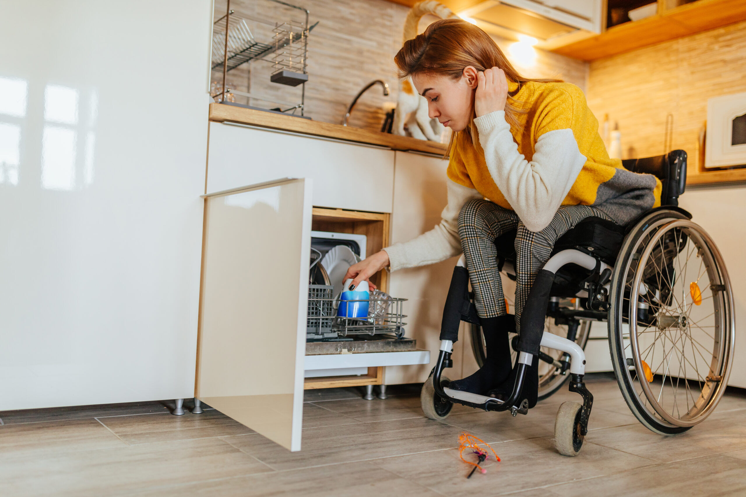 Woman in wheelchair using dishwasher